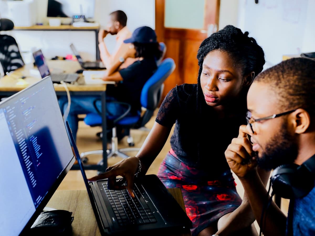 Two young people reviewing code together on a laptop