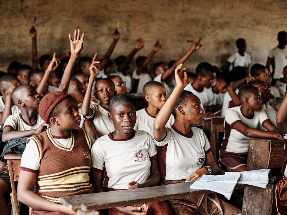 A full classroom of students with their hands raised