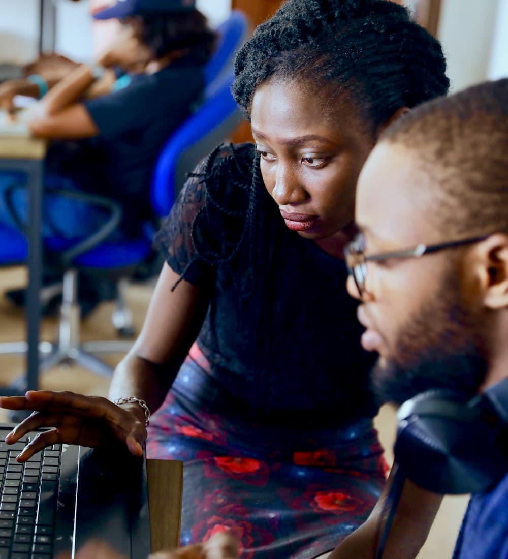 Two young people writing code together on a laptop